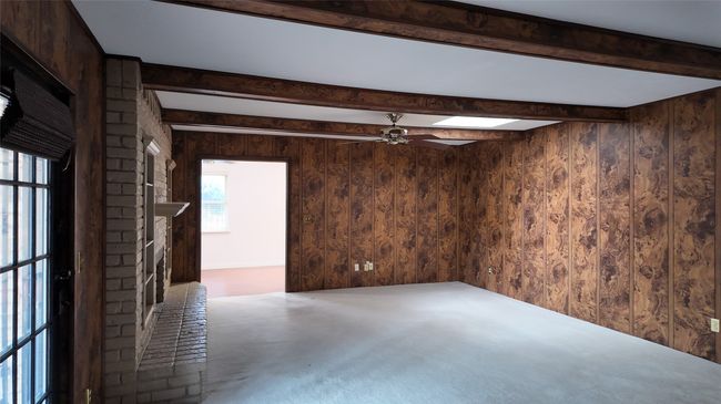 Spare room with ceiling fan, beamed ceiling, a skylight, wood walls, and carpet flooring | Image 20