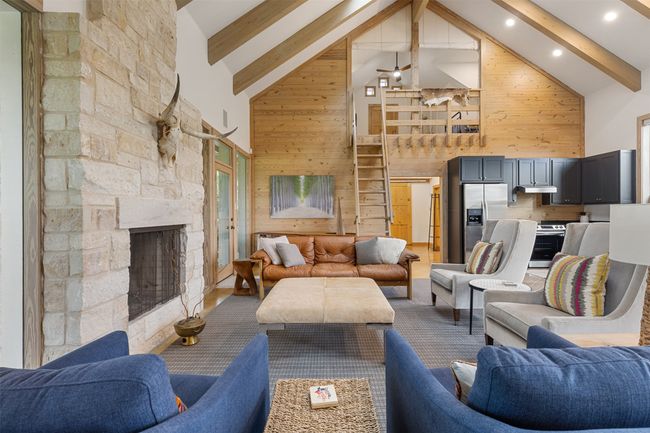 Living area featuring high vaulted ceiling, wood walls, beamed ceiling, and a stone fireplace | Image 18