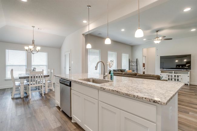 Kitchen featuring a sink, stainless steel dishwasher, wood finished floors, ceiling fan, and light stone counters | Image 15