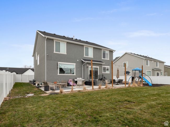 Rear view of house with a patio area, a fenced backyard, a playground, and stucco siding | Image 6