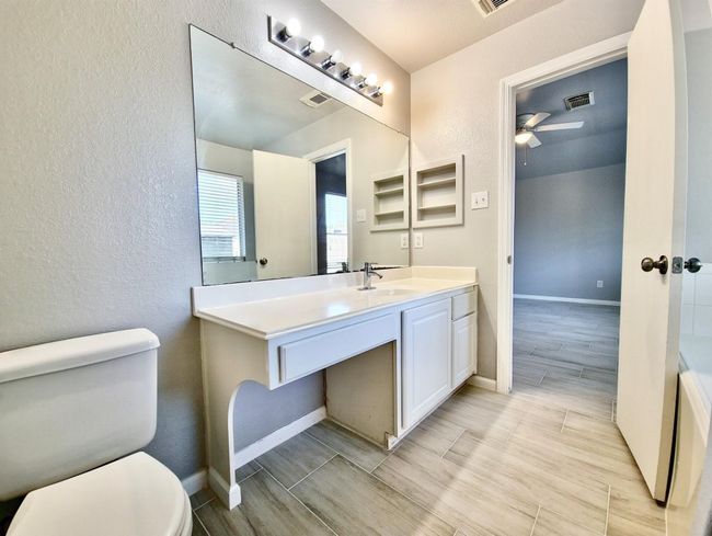 Bathroom with a textured wall, vanity, ceiling fan, and wood tiled floors | Image 15