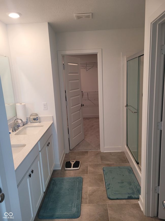 bathroom featuring a stall shower, a walk in closet, and double vanity | Image 17