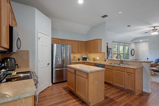 Kitchen with appliances with stainless steel finishes, a sink, a peninsula, vaulted ceiling, and tasteful backsplash | Image 10