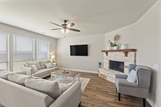 Living room with dark wood-style floors, ceiling fan, and a fireplace | Image 5
