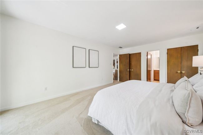 Bedroom with baseboards, light colored carpet, and connected bathroom | Image 33