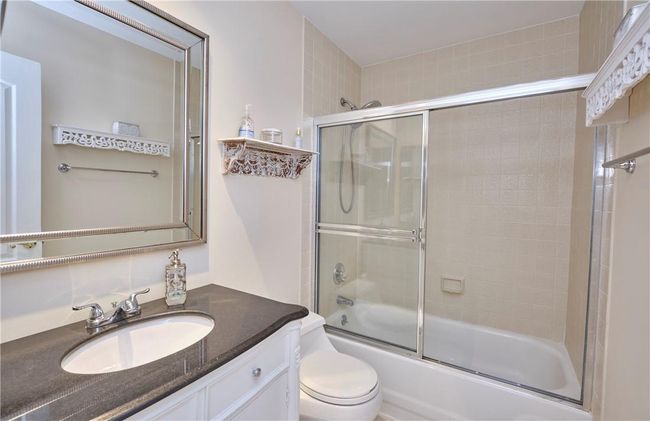 Full bathroom with vanity, bath / shower combo with glass door, and toilet | Image 33