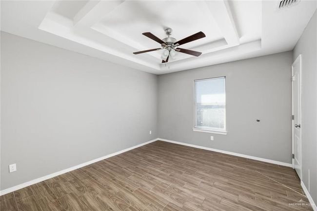Spare room featuring a tray ceiling, wood finished floors, and a ceiling fan | Image 8