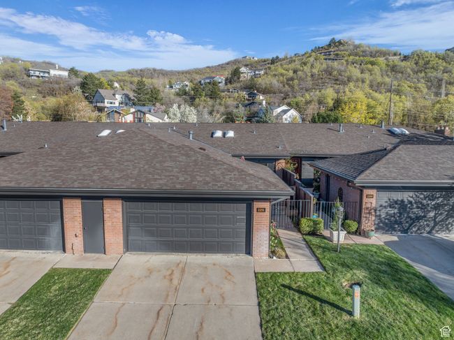 View of front of home with a front yard, a shingled roof, fence, concrete driveway, and brick siding | Image 37