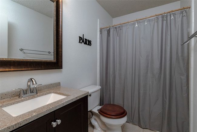 Full bathroom with curtained shower, a textured ceiling, toilet, and vanity | Image 29