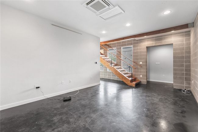 Unfurnished living room featuring tile walls, attic access, recessed lighting, finished concrete floors, and stairs | Image 24