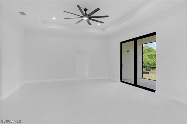 Unfurnished room featuring ceiling fan, concrete floors, and a tray ceiling | Image 28