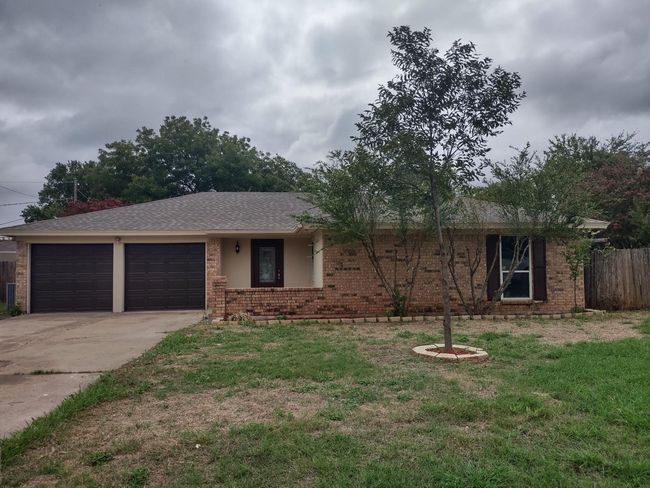 Ranch-style house featuring driveway, brick siding, and a garage | Image 6