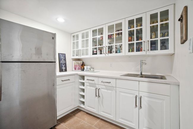 Kitchen with glass insert cabinets, white cabinetry, a sink, and freestanding refrigerator | Image 32
