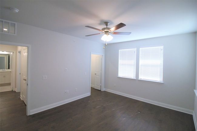 Unfurnished bedroom with visible vents, ceiling fan, dark wood-type flooring, and baseboards | Image 9