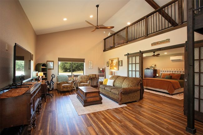 Living area featuring high vaulted ceiling, ceiling fan, hardwood / wood-style floors, a wall mounted air conditioner, and a barn door | Image 34
