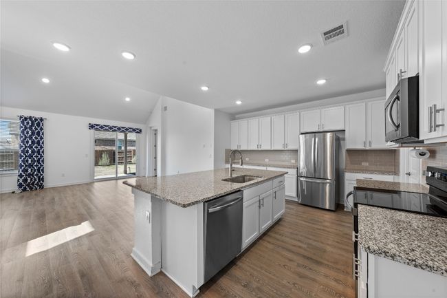 Kitchen with white cabinetry, dark wood-style flooring, stainless steel appliances, a sink, and visible vents | Image 9