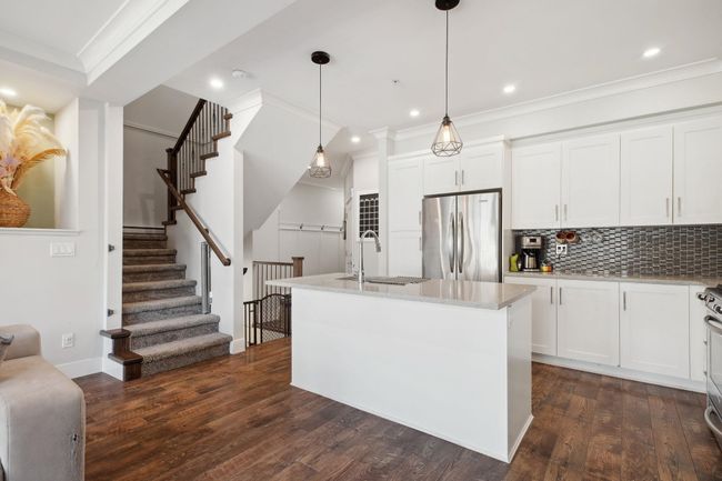 Kitchen with white cabinetry, freestanding refrigerator, a sink, and dark wood finished floors | Image 8