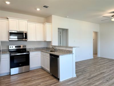 Kitchen includes granite countertops, luxury vinyl plank flooring, 36” upper cabinets with crown molding, a full suite of stainless-steel Whirlpool appliances – including refrigerator with ice maker, recessed lighting, and a large single basin sink. | Image 3