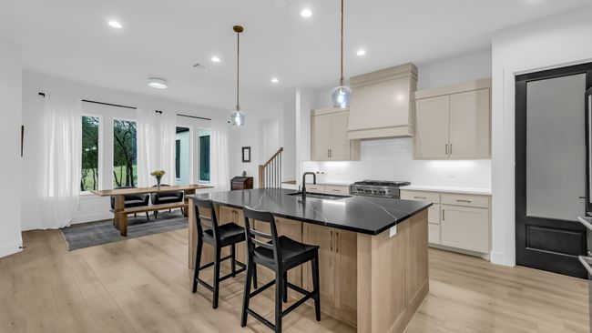 Kitchen featuring a sink, stainless steel range, custom range hood, light wood finished floors, and a breakfast bar area | Image 17