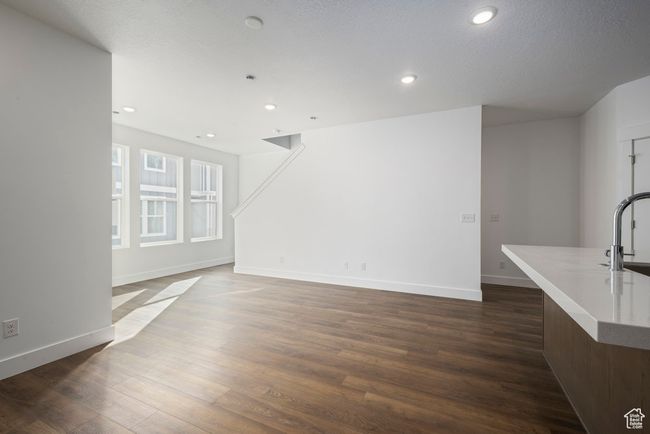 Unfurnished living room featuring dark wood-style floors, recessed lighting, baseboards, and a sink | Image 8