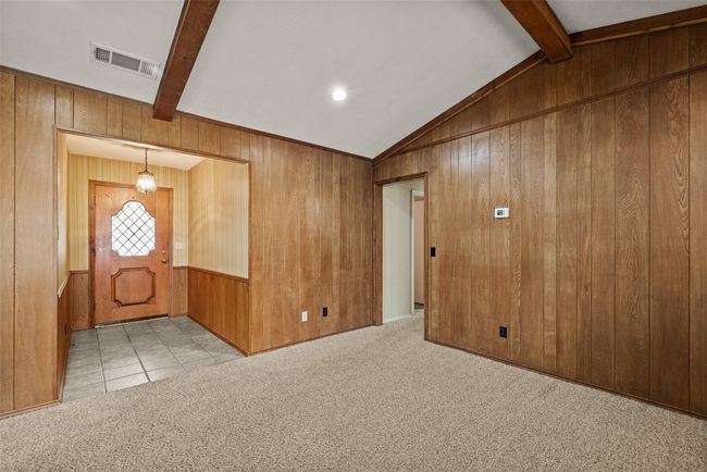 Carpeted foyer entrance with vaulted ceiling with beams, visible vents, and wooden walls | Image 5