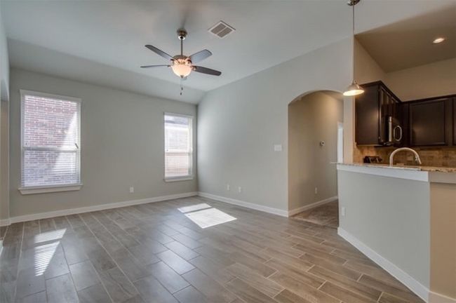 Unfurnished living room with arched walkways, light wood finished floors, a ceiling fan, and baseboards | Image 5