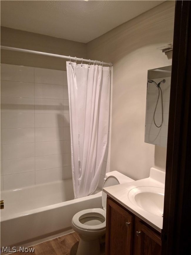 Full bathroom featuring shower / bathtub combination with curtain, wood-type flooring, vanity, and toilet | Image 27