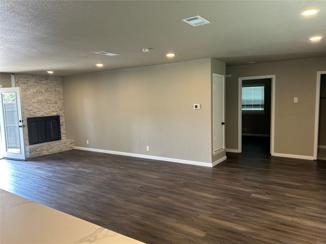 Unfurnished living room with dark wood-style floors, baseboards, recessed lighting, a fireplace, and a textured ceiling | Image 11