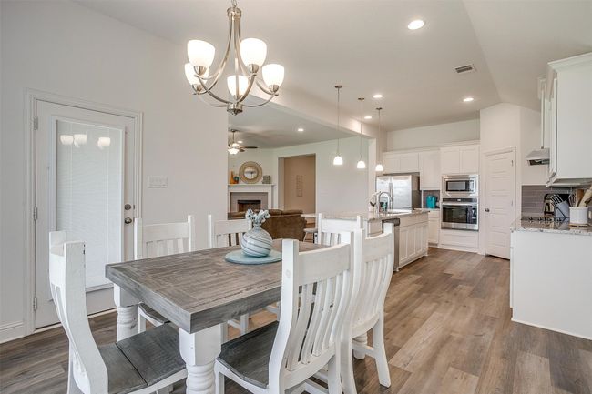 Dining room with a chandelier, wood finished floors, a fireplace, recessed lighting, and a ceiling fan | Image 18