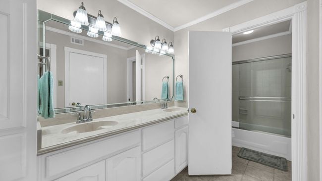 Bathroom with tile patterned flooring, enclosed tub / shower combo, crown molding, and dual bowl vanity | Image 24