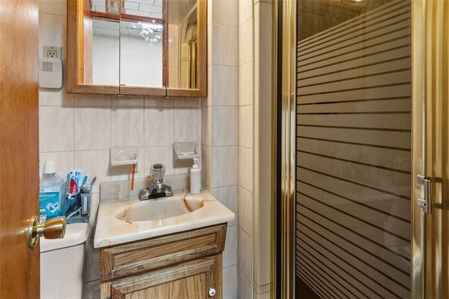 Bathroom featuring radiator heating unit, vanity, tile walls, and decorative backsplash | Image 22