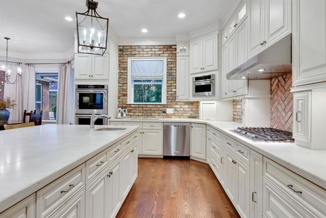 This culinary space features top-of-the-line KitchenAid appliances, including a double oven, five-burner gas range, and a large stainless-steel French-door refrigerator. | Image 15