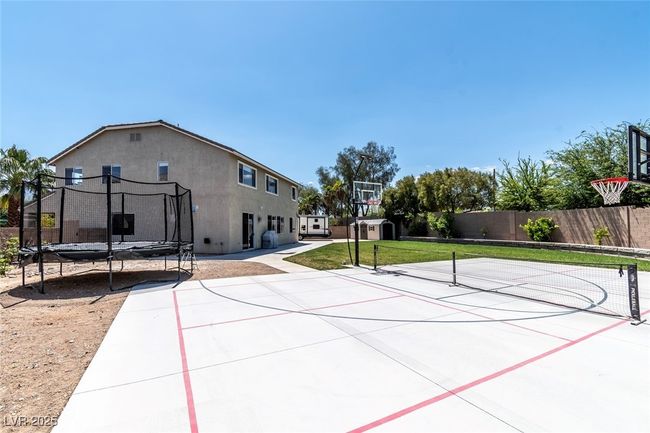 View of basketball court with community basketball court, fence, and a trampoline | Image 39