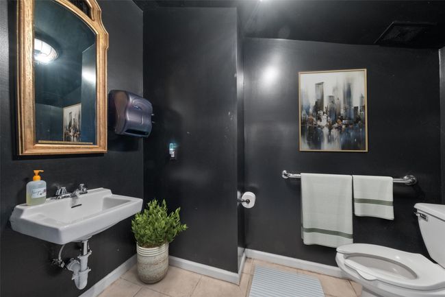 Half bathroom with toilet, tile patterned floors, a sink, baseboards, and visible vents | Image 6