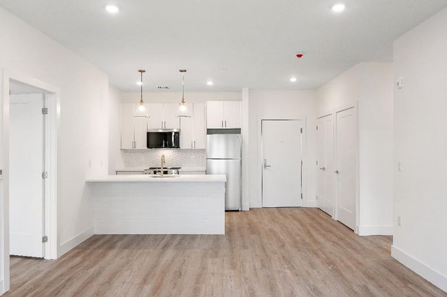 Kitchen with stainless steel microwave, freestanding refrigerator, a sink, tasteful backsplash, and light wood-style floors | Image 10