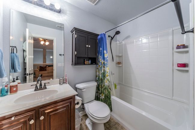 Full bath with toilet, shower / bath combination with curtain, a ceiling fan, vanity, and tile patterned flooring | Image 26