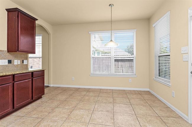 The bright dining area in the kitchen features a charming chandelier and large windows, with a nearby door providing easy access to the backyard patio. | Image 8