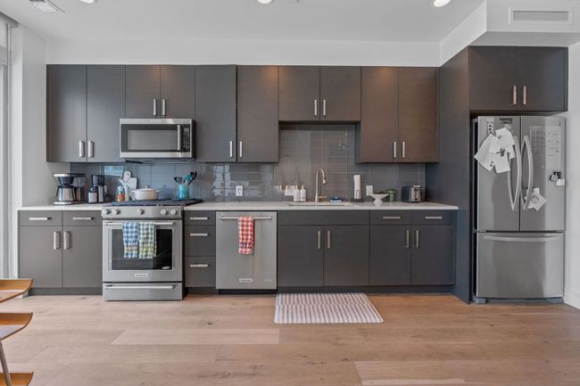 Kitchen with stainless steel appliances, a sink, light countertops, light wood-style flooring, and backsplash | Image 4