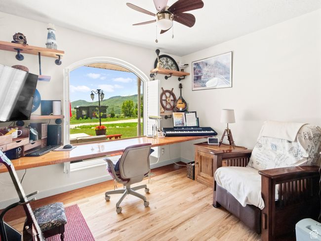 Office area with light wood-type flooring, a ceiling fan, and built in desk | Image 11