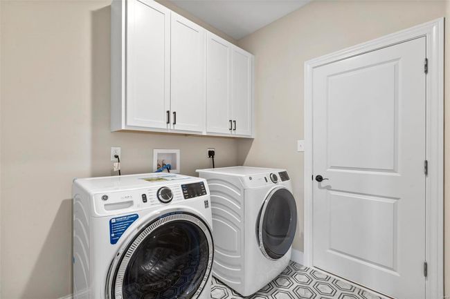 Clothes washing area with washer and clothes dryer, light tile patterned floors, and cabinets | Image 9