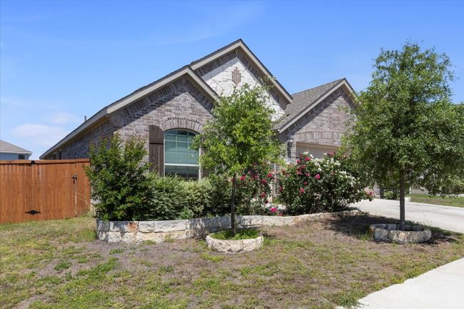 View of front facade with fence, an attached garage, stone siding, and concrete driveway | Image 4