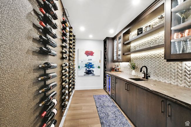 Wine cellar featuring bar with sink, light wood-style floors, recessed lighting, baseboards, and wine cooler | Image 41
