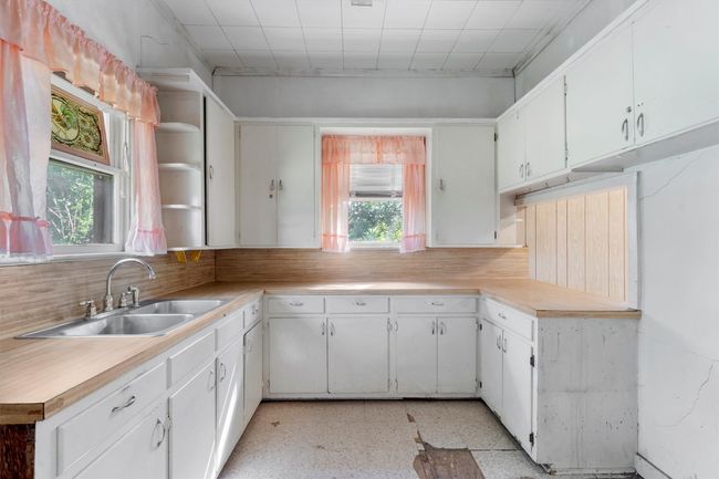Kitchen featuring light countertops, white cabinetry, and a sink | Image 9