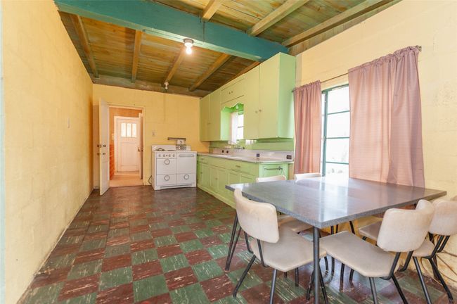 Dining room featuring wood ceiling, concrete block wall, dark floors, and beam ceiling | Image 27