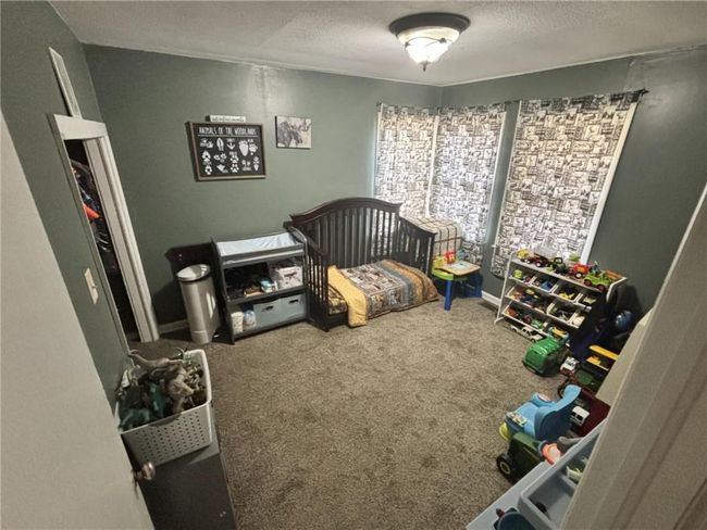 Carpeted bedroom with a textured ceiling and a nursery area | Image 21