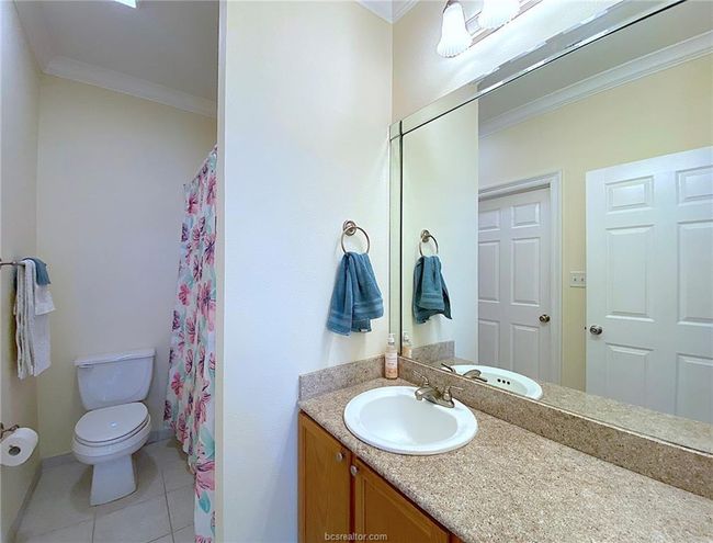Full bath featuring crown molding, toilet, vanity, tile patterned flooring, and curtained shower | Image 8
