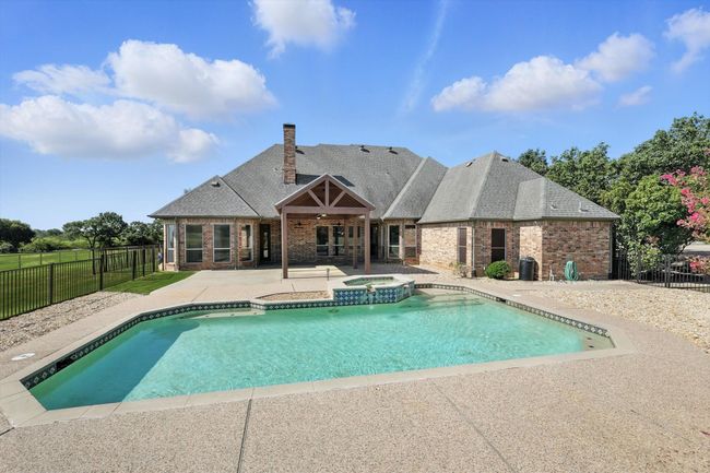 View of pool with a patio, a fenced backyard, and a pool with connected hot tub | Image 5