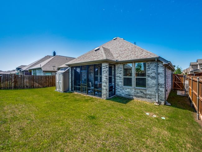 Rear view of house featuring a storage shed, a lawn, a fenced backyard, brick siding, and a sunroom | Image 34