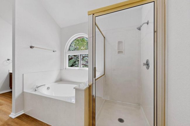 Bathroom featuring a shower stall, a bath, wood finished floors, and lofted ceiling | Image 19