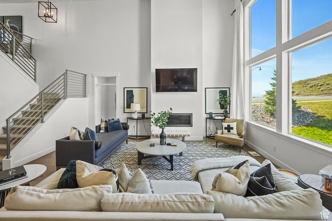 Living room featuring a towering ceiling, wood finished floors, and stairway | Image 8